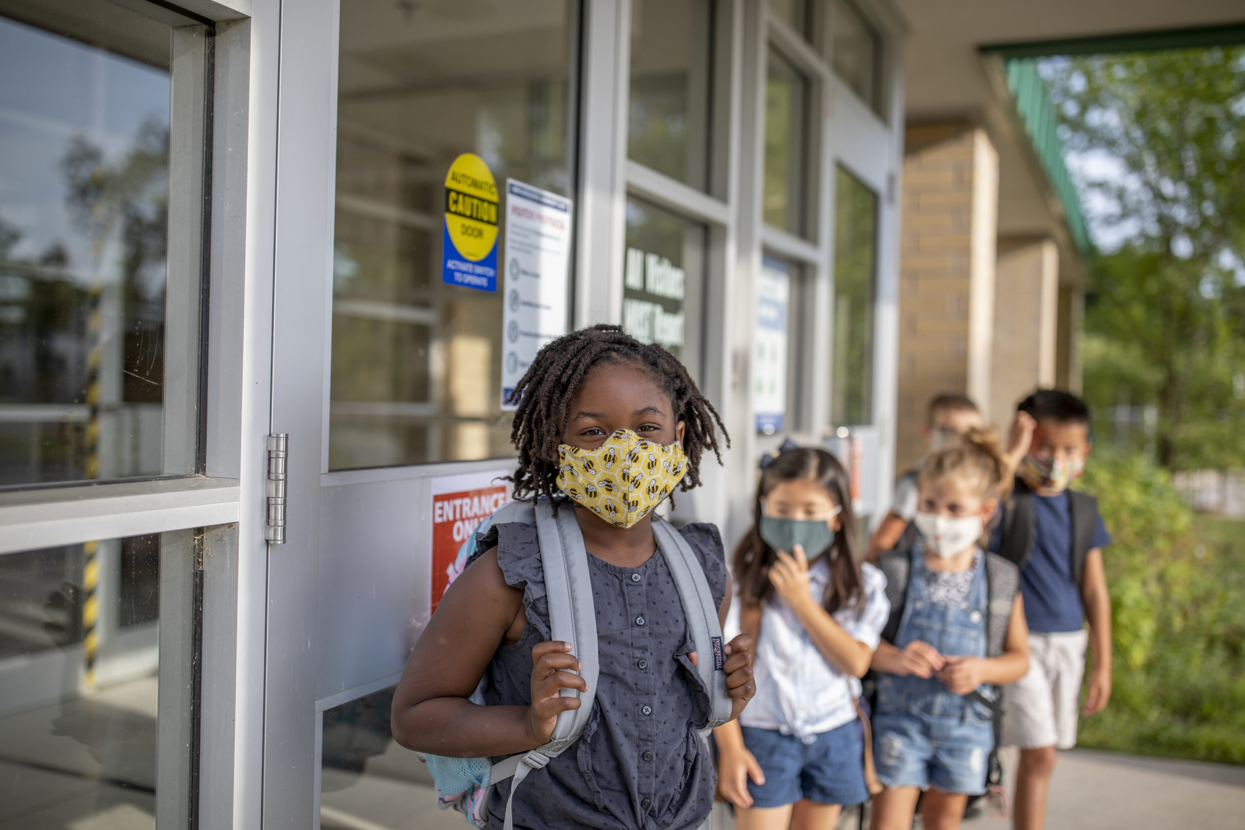Diverse group of elementary school kids go back to school wearing masks